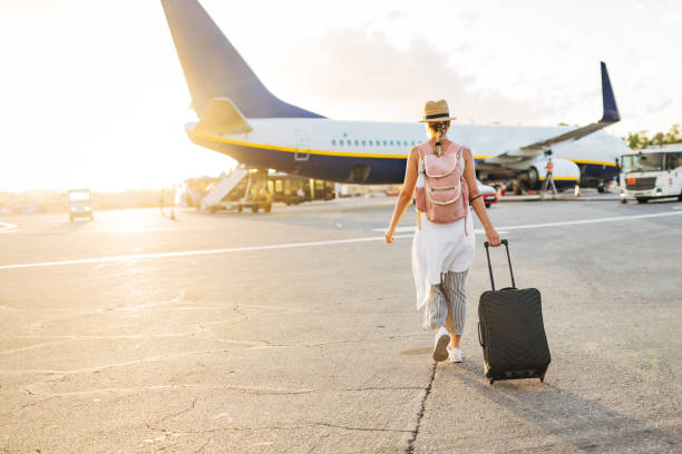 飛行機に向かって歩き、搭乗して休暇を始める準備ができている女性の後ろ姿 - リトリート ストックフォトと画像